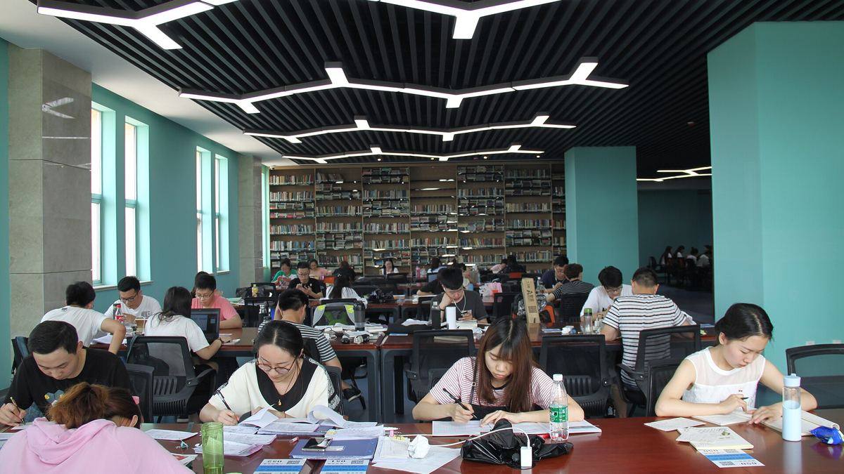 Students studying at long tables in a university library